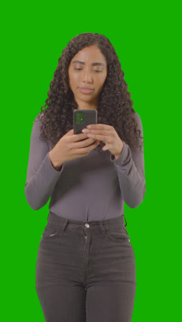 Vertical-Video-Three-Quarter-Length-Vertical-Video-Portrait-Of-Vertical-Video-Woman-Text-Messaging-On-Mobile-Phone-Against-Green-Screen